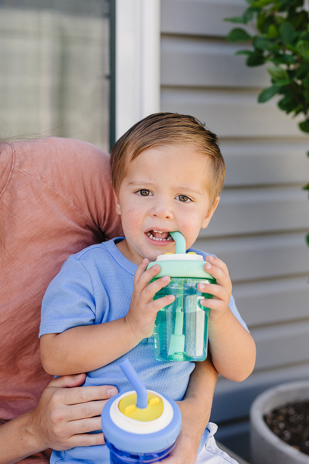 Toddler drinking from a mint Poki Yoki straw cup on a parent's lap
